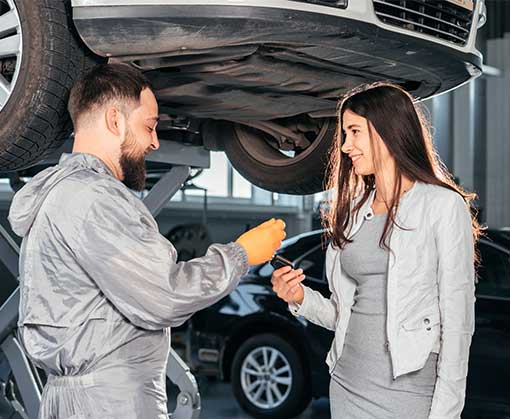 NCC Auto Mechanic giving the car keys to his female customer in workshop at auto repair center